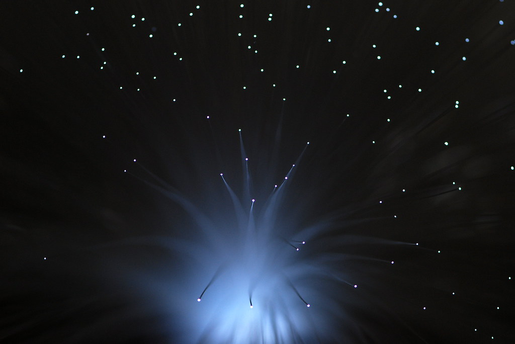 Abstract burst of fiber optic light points on a dark background
